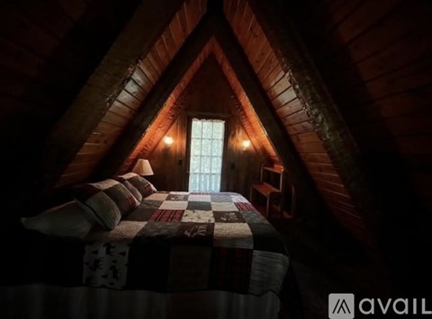 A cozy bedroom with a bed in the center and a window above it.