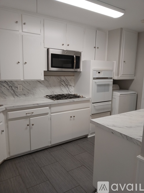 A kitchen with white cabinets and a marble countertop.