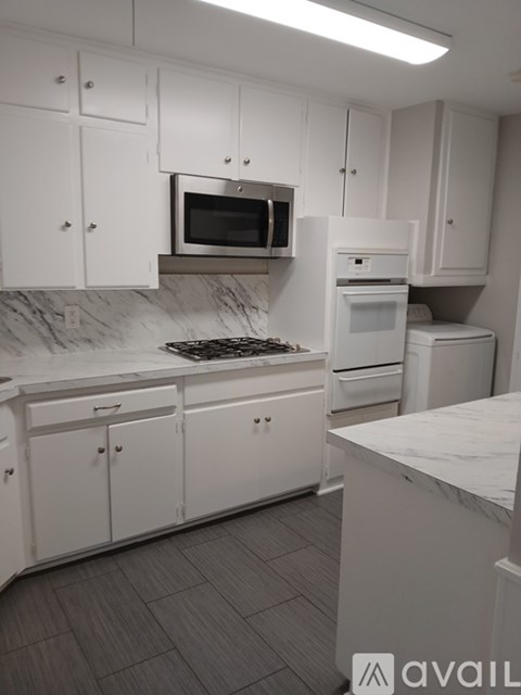 A kitchen with white cabinets and a marble countertop.