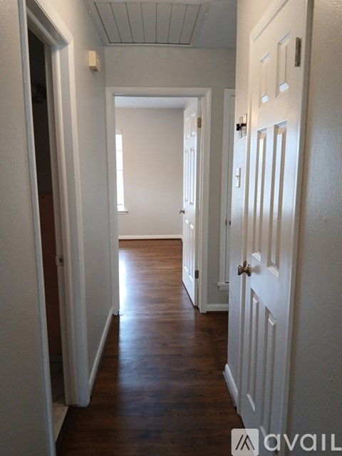 A hallway with white doors and wooden floors.