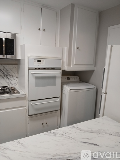 A kitchen with white appliances and cabinets.