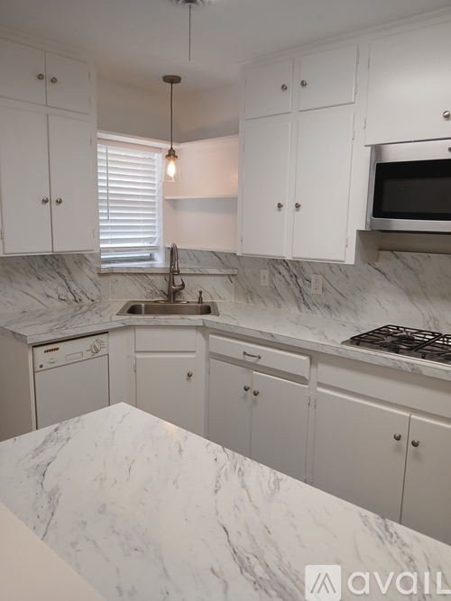 A kitchen with white cabinets and marble countertops.