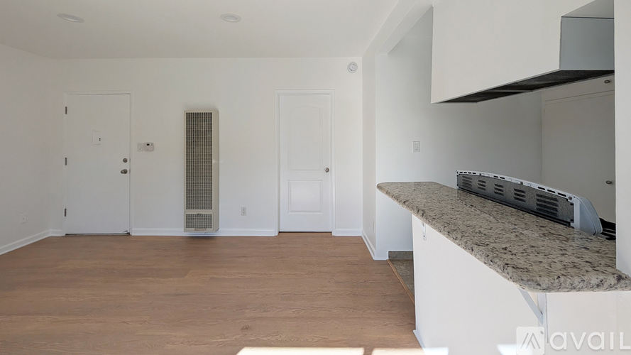 A spacious, empty room with a counter and cabinets on the right.