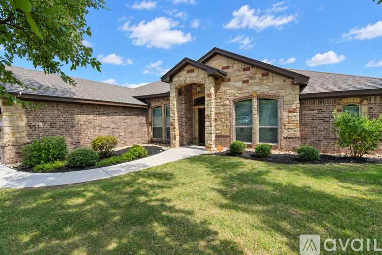 A house with a stone facade and a green lawn in front.