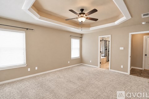 A spacious room with a ceiling fan and a window with blinds.