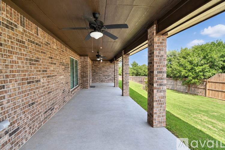 A patio with a ceiling fan and brick columns.