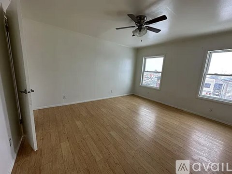 A room with a ceiling fan and two windows.