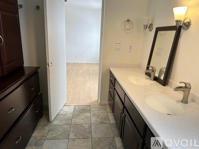 A bathroom with a sink, mirror, and wooden floor.