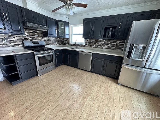 A kitchen with black cabinets and a wooden floor.