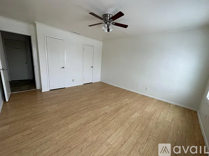 A room with a ceiling fan and wooden flooring.