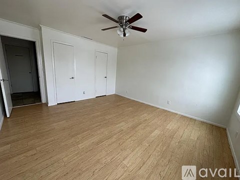 A room with a ceiling fan and wooden flooring.