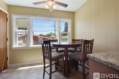 A dining room with a table and chairs and a ceiling fan.