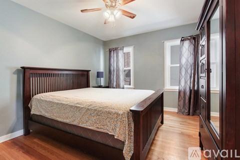 A bedroom with a bed, wooden headboard, and a ceiling fan.