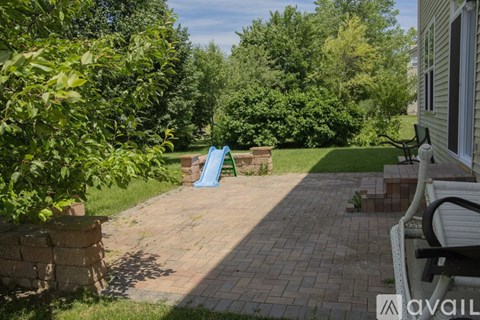 A backyard with a brick patio and a blue slide.