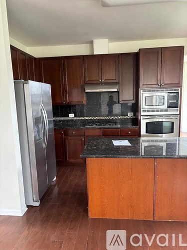 A kitchen with wooden cabinets and a stainless steel refrigerator.