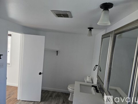A white bathroom with a toilet, sink, and mirror.