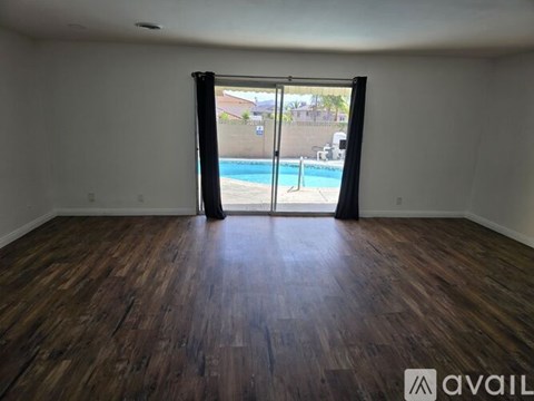 A room with wooden flooring and a sliding glass door leading to a pool.
