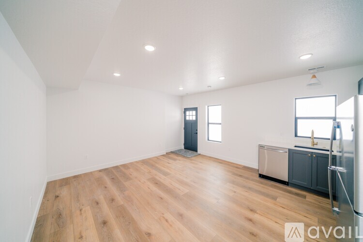 A spacious room with wooden flooring and a cabinet with a fridge.