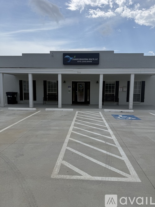 A parking lot in front of a building with a sign that reads "AVAIL".