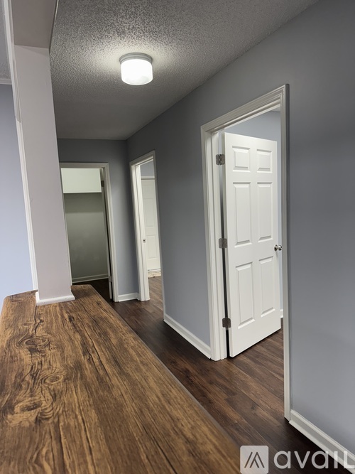 A hallway with a white door and wooden flooring.