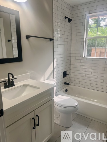 A white toilet sits in a bathroom with a white sink and a window.