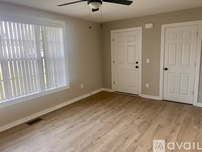 A room with a ceiling fan and two doors.