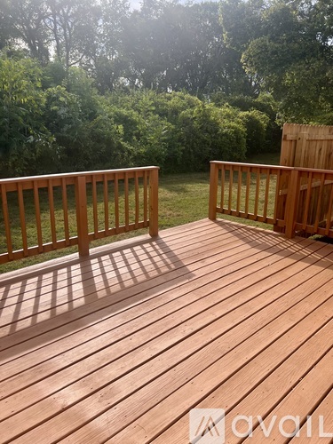 A wooden deck with a railing and trees in the background.