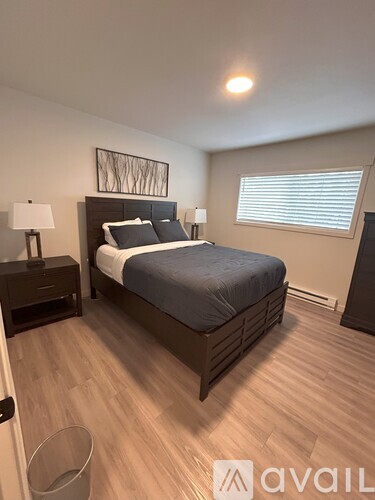 A bedroom with a bed, nightstand, and lamp.