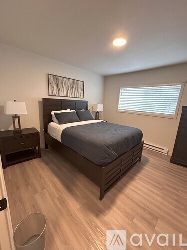 A bedroom with a bed, nightstand, and lamp.