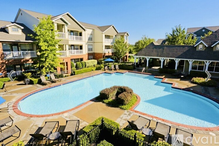 A large swimming pool surrounded by lounge chairs and apartment buildings.