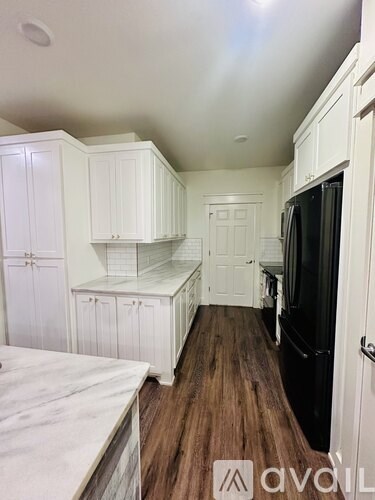 A kitchen with white cabinets and a black refrigerator.