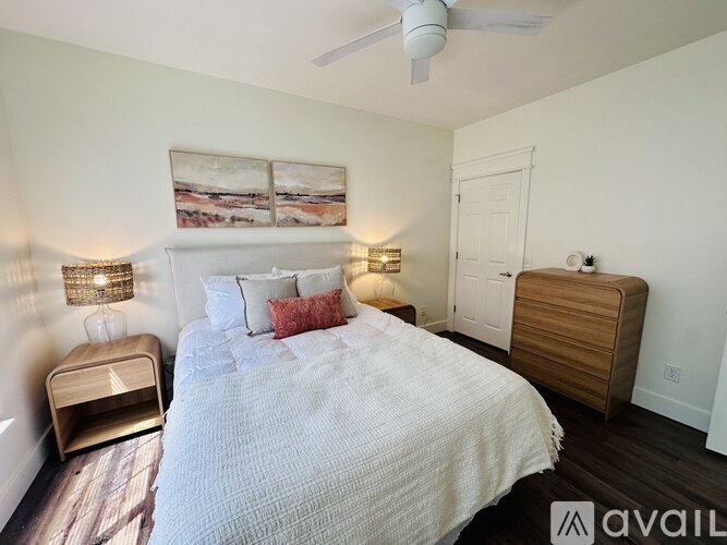 A bedroom with a bed, nightstand, and a painting on the wall.