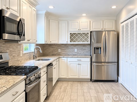 A kitchen with white cabinets and a stainless steel refrigerator.