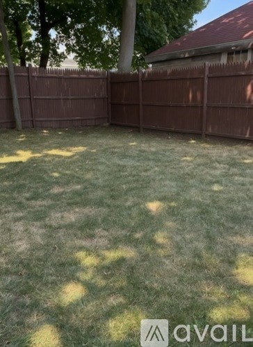 A backyard with a brown fence and green grass.