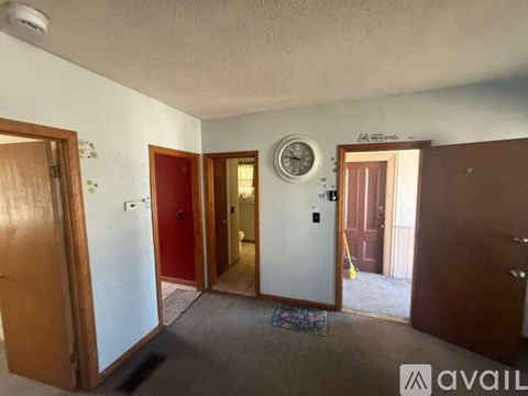 A room with a clock on the wall and a door on the right.