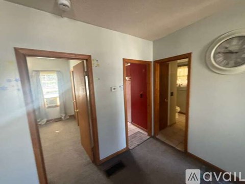 A room with a clock on the wall and a red door.