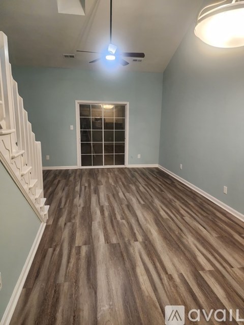 A room with wooden flooring and a white staircase.