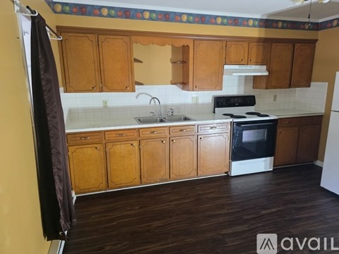 A kitchen with wooden cabinets and a white stove top oven.