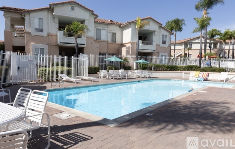 A pool area with chairs and a building in the background.