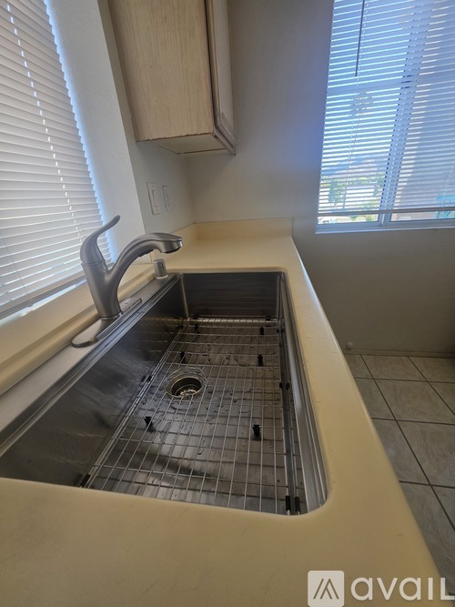 A kitchen sink with a faucet and a window with blinds.