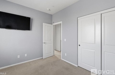 A room with a flat screen TV mounted on the wall and two white doors.