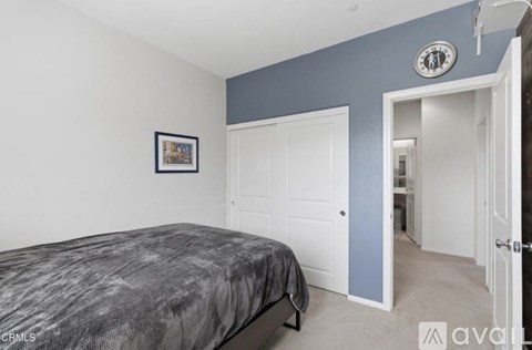 A bedroom with a bed, a clock, and a picture on the wall.
