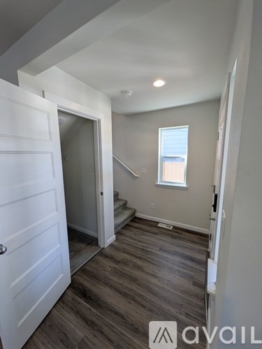A hallway with a white door and a window with a view of a building outside.