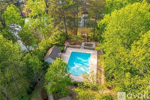 A bird's eye view of a house with a pool surrounded by trees.