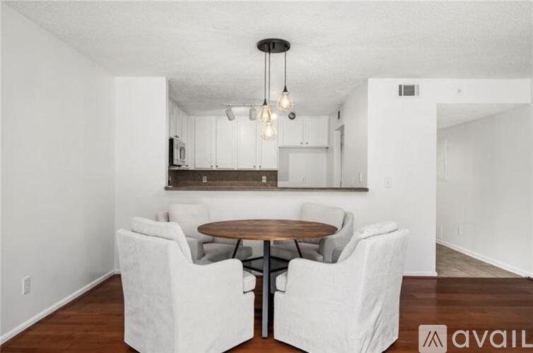 A dining area with a round table and white chairs.