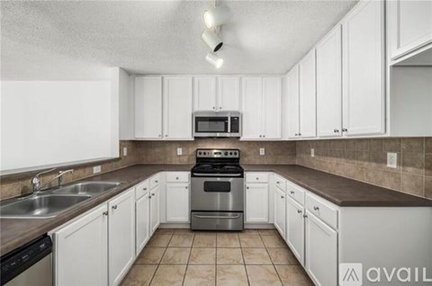 A kitchen with white cabinets and a stainless steel stove.