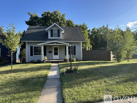 A small white house with a grey roof and a small porch.
