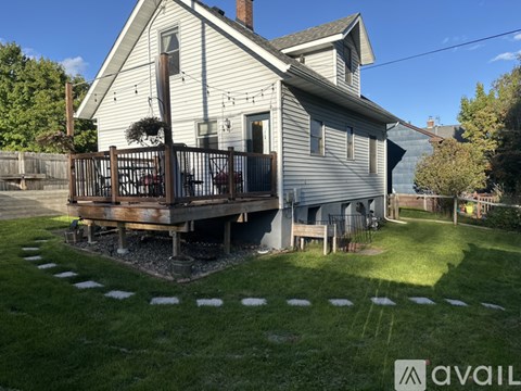 A house with a white exterior and a deck in the backyard.
