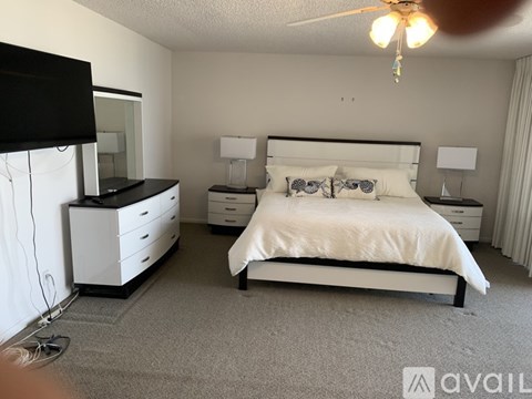 A bedroom with a large bed, a dresser, and a TV.
