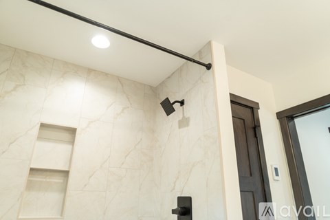 A bathroom with a marble wall and a black door.